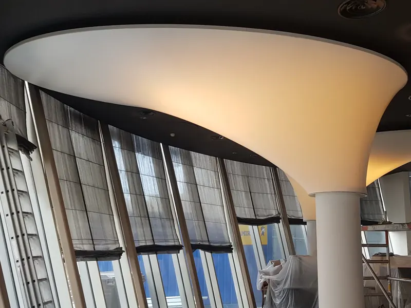 Curved stretch ceiling plane with a concealed curtain track at the windows