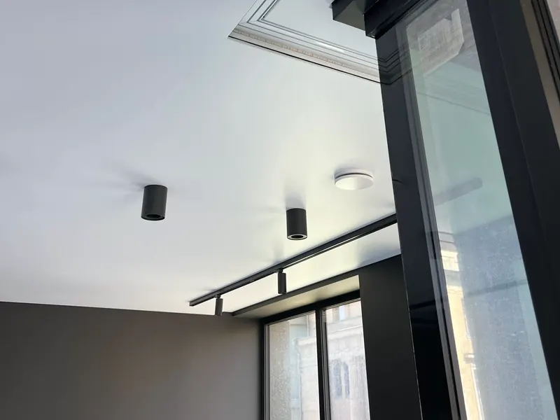 Shadow gap profile — the gap between ceiling plane and wall beside black window frames, without a curtain track
